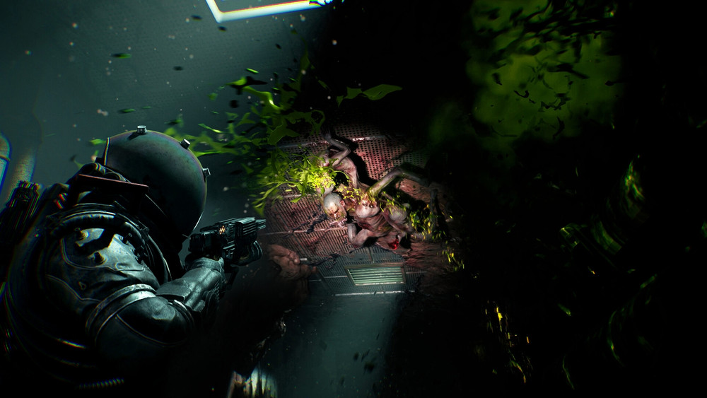 Capture d’écran d’un jeu vidéo d’horreur et de science-fiction en vue à la troisième personne. Un personnage en combinaison spatiale sombre et casque intégral, armé d’un fusil futuriste, fait face à une créature monstrueuse dans un environnement clos et métallique rappelant l’intérieur d’un vaisseau spatial ou d’une station orbitale. La créature, humanoïde mais déformée, possède une peau pâle et organique, avec des excroissances verdâtres et des membres anormaux. Elle surgit d’une bouche d’aération, entourée d’une explosion de fluides et de particules vertes lumineuses qui accentuent l’ambiance cauchemardesque. La scène baigne dans une atmosphère oppressante avec des jeux d’ombre et de lumière, renforçant la tension dramatique. Ce type de visuel évoque des licences vidéoludiques comme Dead Space, The Callisto Protocol ou d’autres survival horror spatiaux, où le joueur doit survivre à des abominations extraterrestres dans un univers claustrophobique.