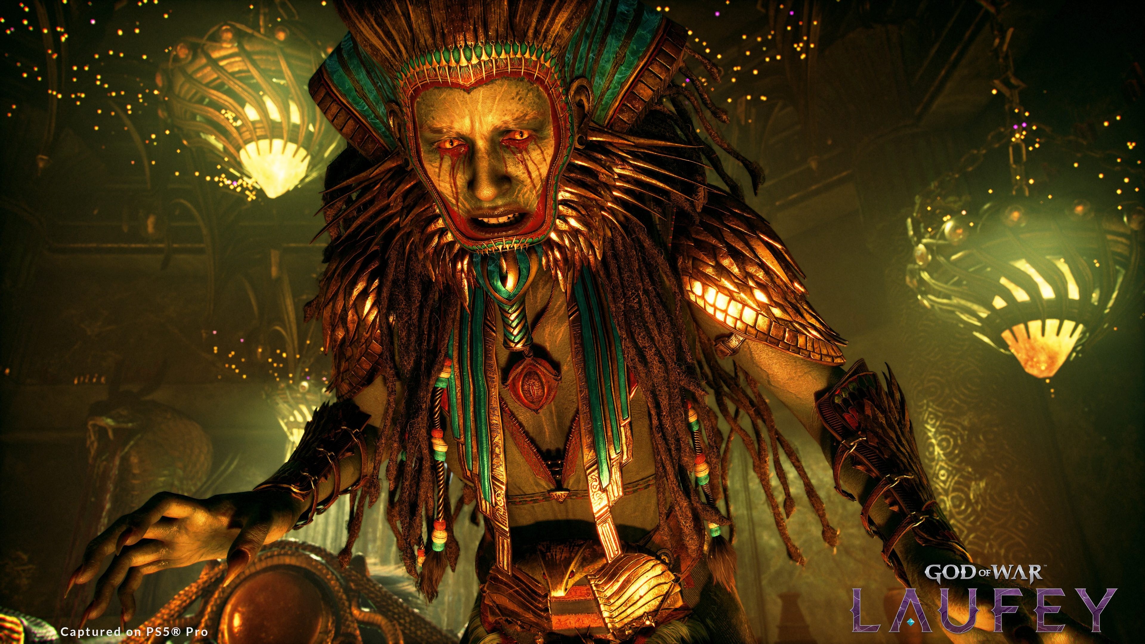 Capture de God of War: Laufey sur PS5 Pro montrant un imposant personnage aux yeux rouges, vêtu d’une armure cérémonielle ornée de plumes, de dorures et de turquoise. Il se penche vers l’avant dans une salle sombre éclairée par de grandes lanternes dorées.