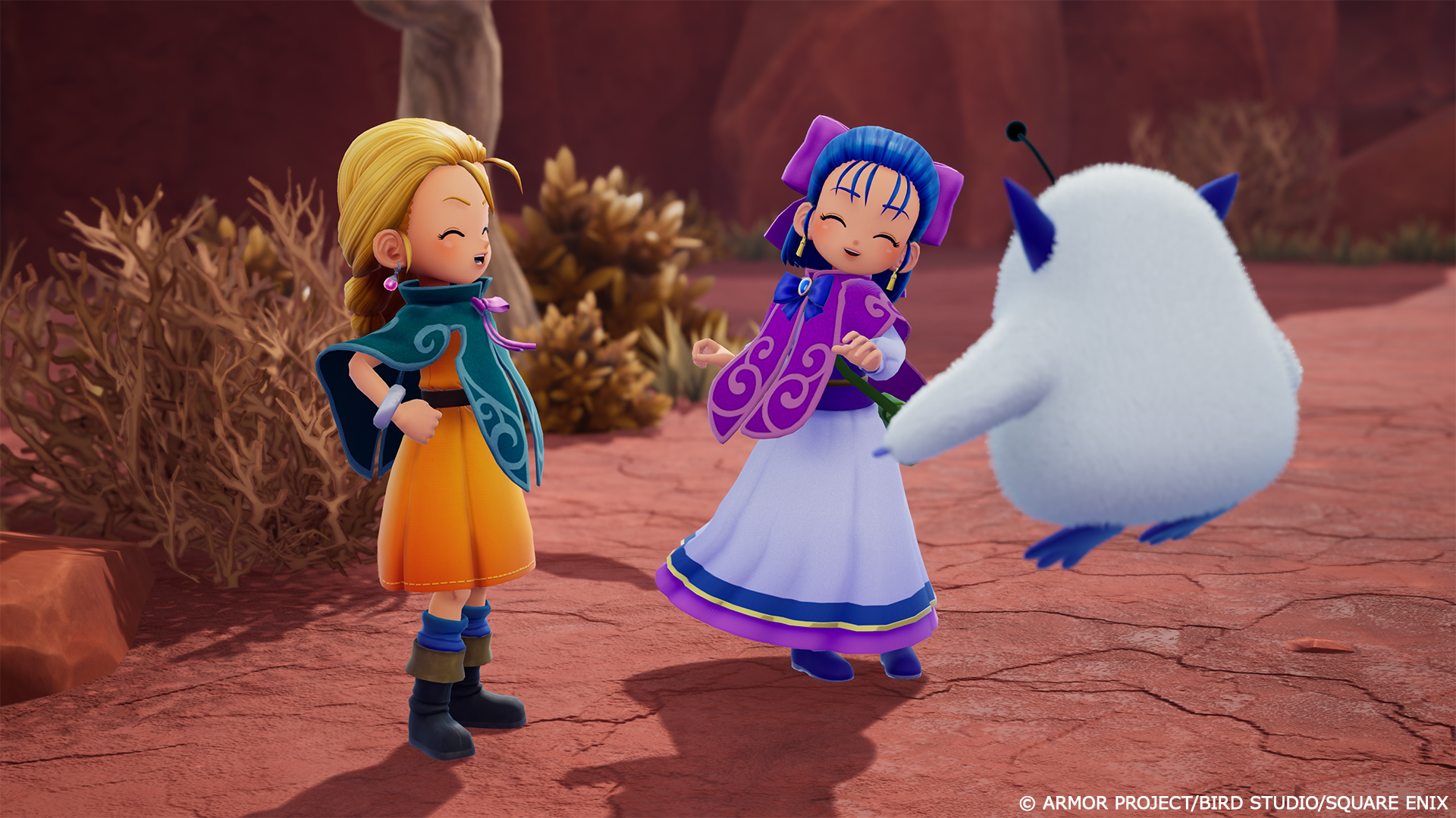 Capture d’écran de Dragon Quest Monsters montrant deux jeunes personnages souriants discutant avec une créature blanche et ronde aux petites cornes bleues. La scène se déroule dans un décor rocheux rougeâtre, avec une ambiance chaleureuse et légère proche d’une cinématique d’aventure.