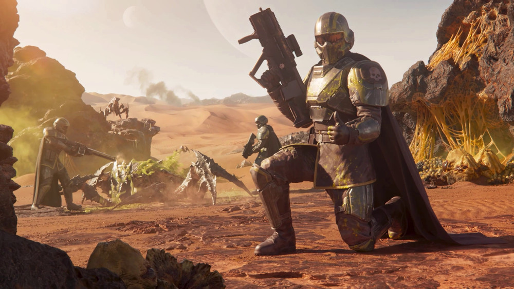 Scène de combat futuriste dans un désert extraterrestre. Au premier plan, un soldat en armure lourde métallique avec un casque intégral et une cape sombre est agenouillé, tenant un fusil d’assaut futuriste. Ses épaulières arborent un motif de crâne, accentuant son allure intimidante. À l’arrière-plan, deux autres soldats affrontent une créature insectoïde massive au corps blindé et hérissé de pointes, typique d’un environnement hostile de science-fiction. Le décor est constitué de dunes de sable rouge, de formations rocheuses abruptes et d’étranges nids organiques jaune vif accrochés aux falaises, suggérant une planète infestée de créatures aliens. Dans le ciel, une lune ou une planète proche est visible, renforçant l’atmosphère d’exploration spatiale et de guerre intergalactique.