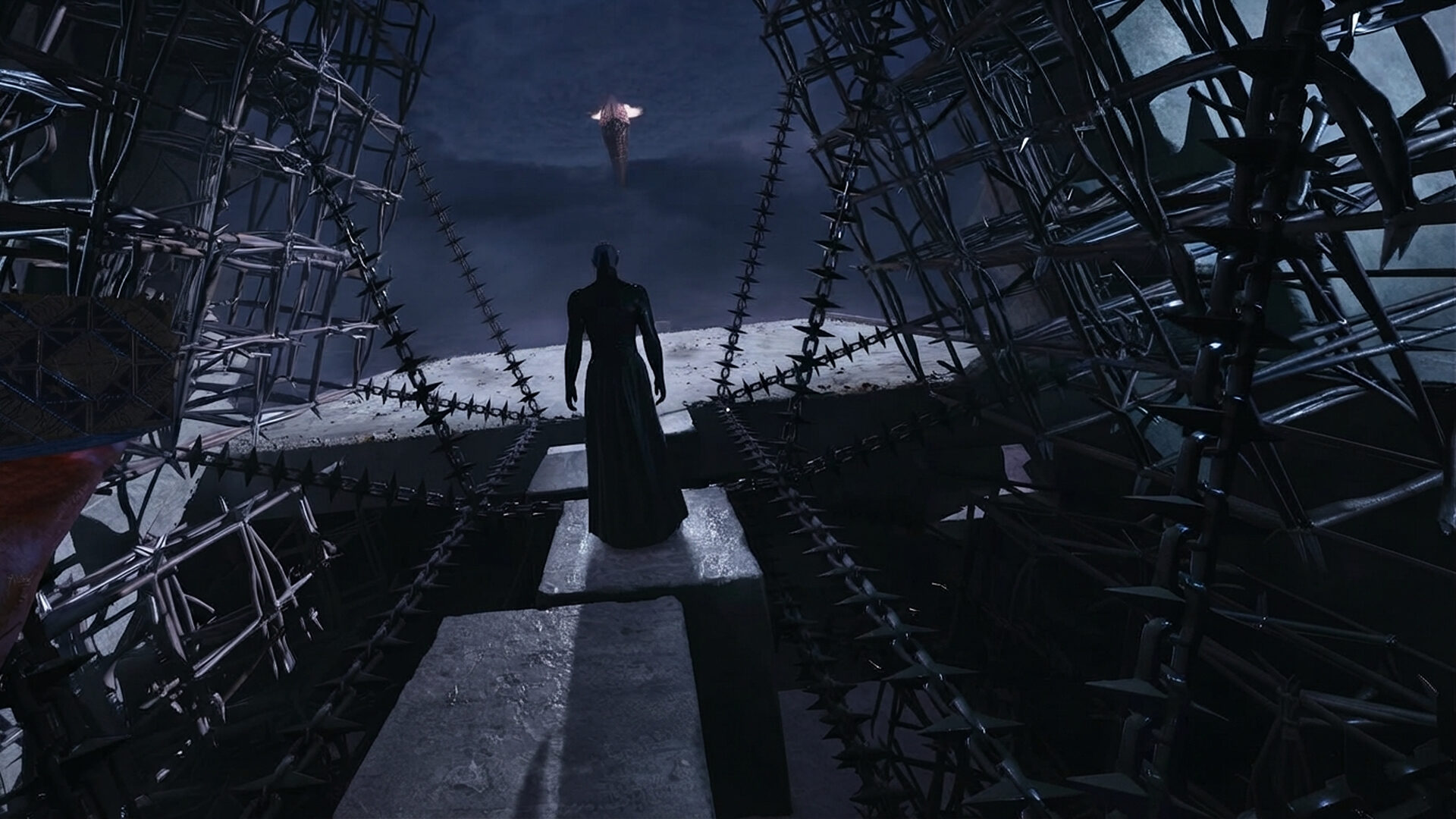 Capture d’un jeu d’horreur montrant une silhouette humanoïde en robe noire avançant entre d’immenses structures métalliques hérissées de pointes, dans un environnement sombre et oppressant sous un ciel nocturne.