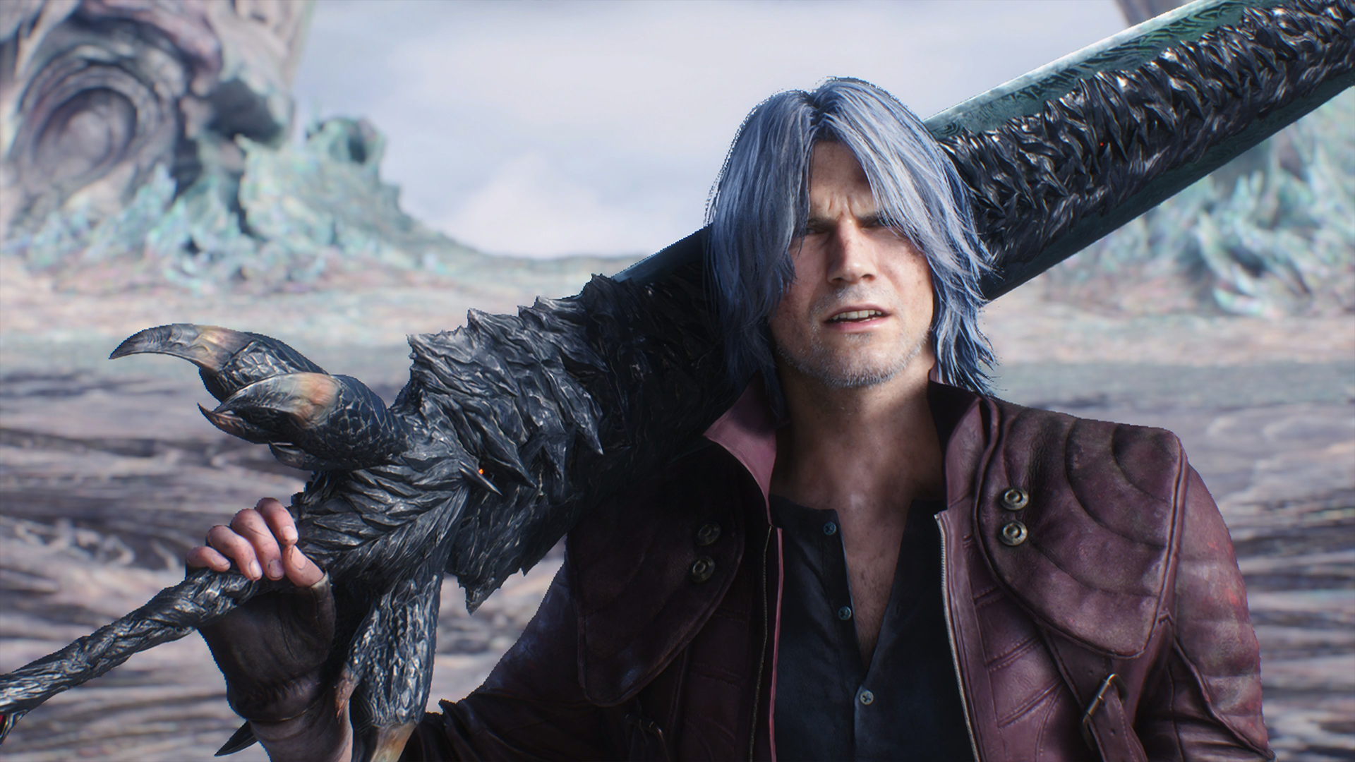 Capture d’écran de Devil May Cry 5 montrant Dante en gros plan, cheveux gris-bleu et veste rouge, portant une immense épée et une arme démoniaque noire sur l’épaule. Le décor clair et organique en arrière-plan renforce l’ambiance surnaturelle et cinématique de la scène.
