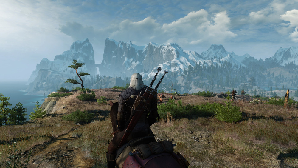Capture de gameplay de fantasy en monde ouvert montrant un guerrier aux cheveux blancs monté à cheval, vu de dos, observant un vaste paysage côtier. Des montagnes enneigées dominent l’horizon sous un ciel nuageux, tandis que des forêts, falaises et chemins s’étendent au loin, mettant en valeur l’exploration et l’ampleur de l’environnement.