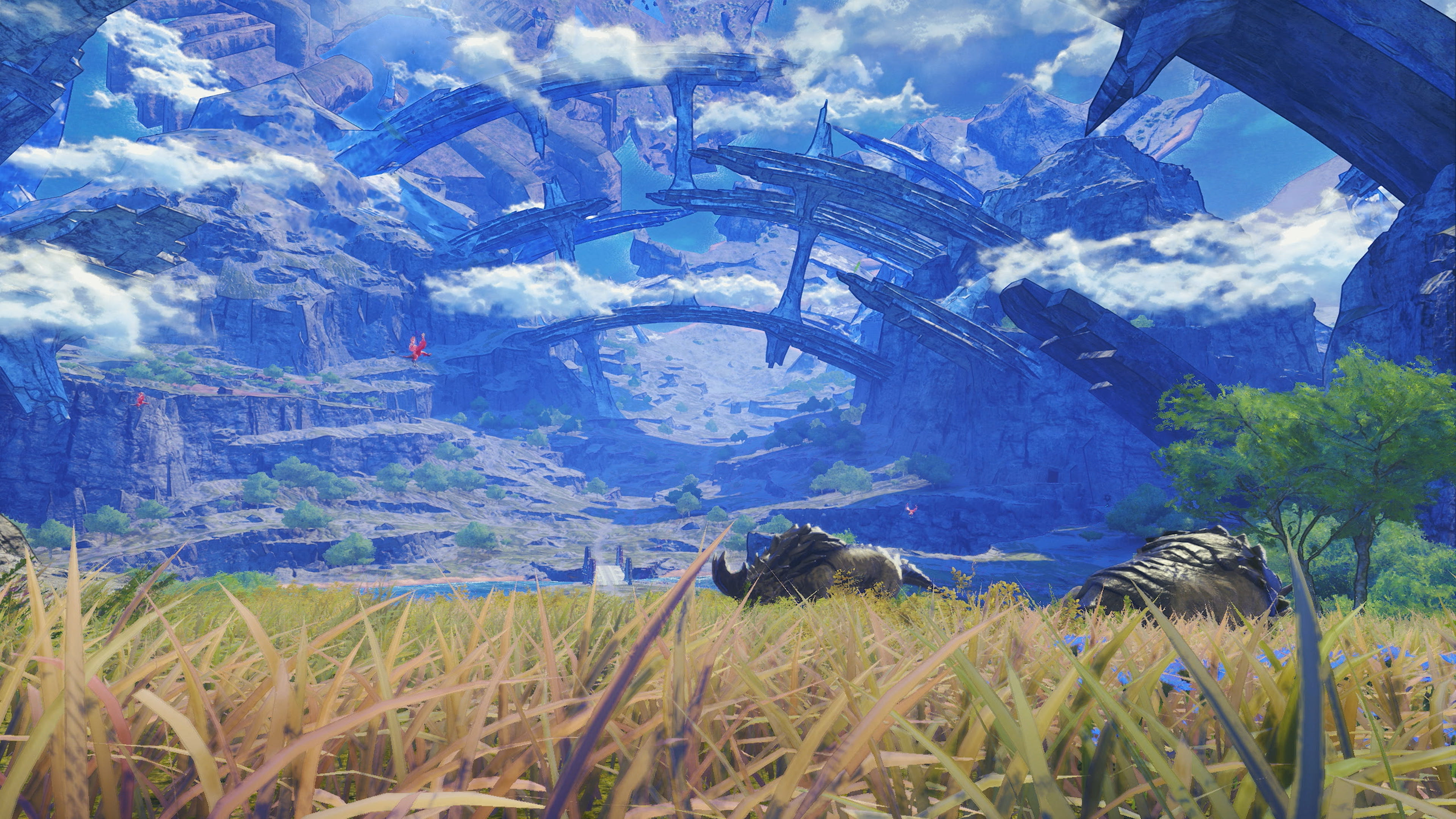 Capture d’écran d’un jeu vidéo de style JRPG montrant une vaste vallée rocheuse baignée de lumière, avec de grandes structures anciennes suspendues dans le ciel. Au premier plan, des herbes hautes et des créatures sombres contrastent avec les falaises bleutées, les nuages et l’ambiance d’exploration grandiose.