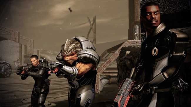 Image tirée du jeu vidéo Mass Effect 2, montrant trois membres d’une escouade armée prêts à l’action dans un environnement désertique et industriel en ruine. À gauche, le commandant Shepard, en combinaison noire tactique, pointe une arme futuriste en direction d’une menace hors champ. Au centre, un Krogan — imposante créature extraterrestre à la peau écailleuse et à la carrure massive — porte une armure lourde grise et noire, tenant fermement un fusil à deux mains. À droite, un autre membre de l’équipe, probablement Jacob Taylor, en combinaison noire ornée du logo de Cerberus, observe l’arrière avec vigilance, arme en main. L’arrière-plan présente des structures métalliques délabrées, des escaliers en béton et des débris, dans une ambiance ocre et poussiéreuse typique des zones de conflit de la série. L’image souligne l’aspect tactique, militaire et coopératif de Mass Effect 2, où humains et extraterrestres s’unissent face à des menaces galactiques dans un univers de science-fiction riche et immersif.