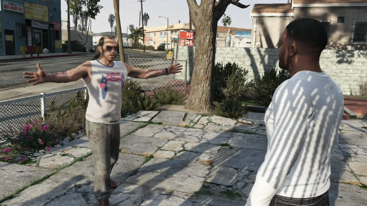 Scène emblématique de Grand Theft Auto V, montrant une interaction entre deux des protagonistes du jeu : Trevor Philips et Franklin Clinton. Trevor, situé à gauche, adopte une posture expressive avec les bras grands ouverts, vêtu d’un débardeur blanc taché portant l’inscription "Del Perro Pier", un pantalon sale et des sandales. Son attitude est théâtrale, typique de son tempérament instable et imprévisible. En face de lui, à droite, Franklin, vêtu d’un sweat blanc à manches longues et d’un jean foncé, l’observe avec calme, les bras le long du corps. Ils se tiennent dans une allée pavée entre des habitations de banlieue typiques de Los Santos, avec un arbre, quelques buissons et un muret en fond. Au loin, on aperçoit un quartier urbain avec des bâtiments modestes, un panneau "For Sale", des palmiers et une enseigne de magasin ("Meat Market Plus"). La scène illustre bien les contrastes de personnalité entre les personnages dans GTA V, dans un cadre urbain réaliste et détaillé, mêlant narration cinématographique et liberté d’exploration.