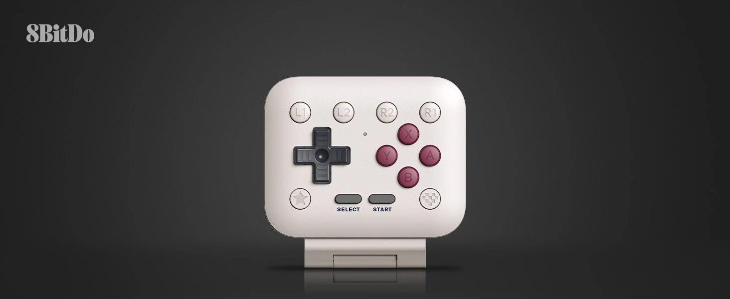 Manette 8BitDo FlipPad blanche sur fond noir, au design compact et carré, avec croix directionnelle, boutons X, Y, A et B bordeaux, gâchettes L1, L2, R2 et R1, ainsi que boutons Select et Start. Le logo 8BitDo apparaît en haut à gauche.