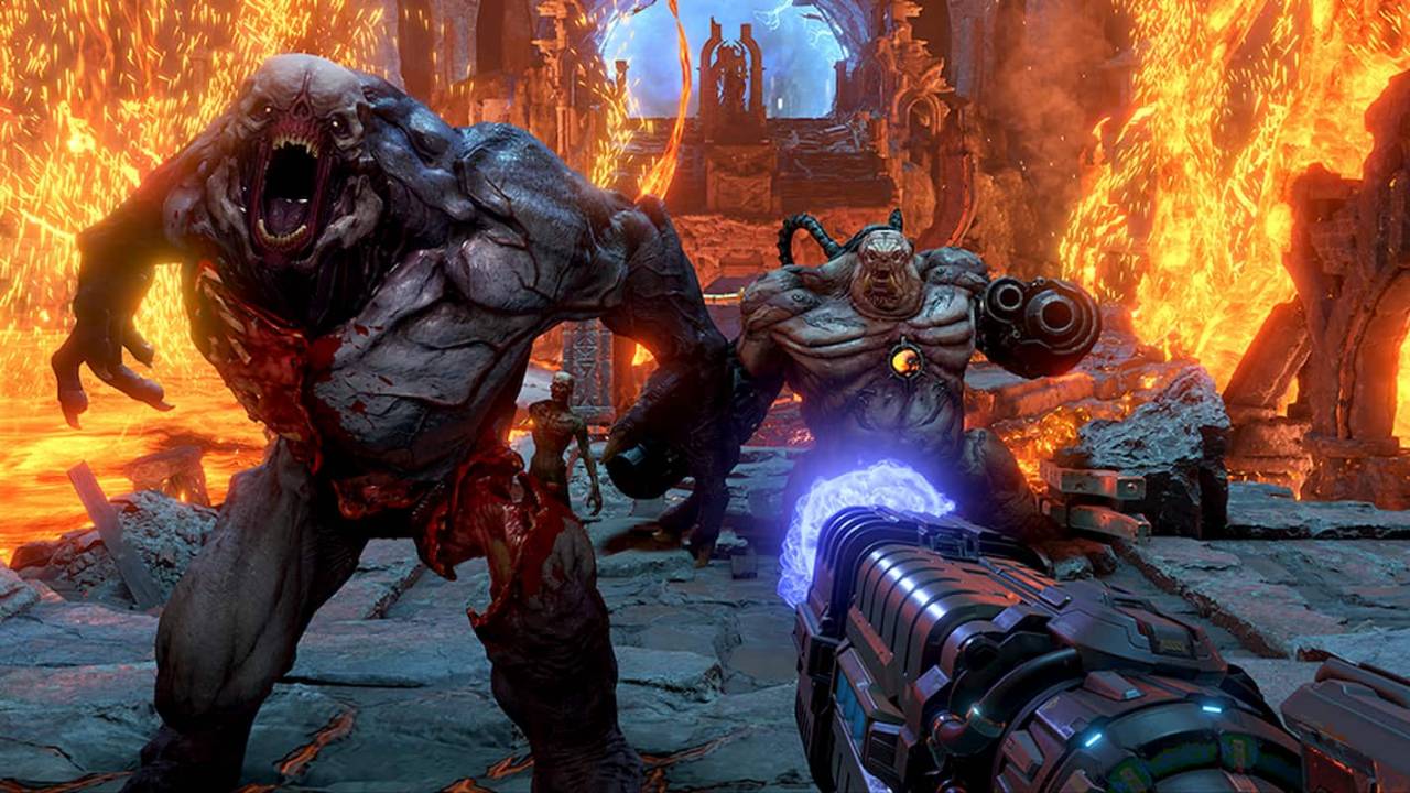 Capture d’écran intense et survoltée du jeu DOOM Eternal, en vue à la première personne, mettant en scène le joueur affrontant plusieurs démons monstrueux dans un environnement infernal. Au premier plan, le canon futuriste du joueur, chargé d’énergie bleutée, est pointé vers deux ennemis imposants qui foncent droit sur lui. À gauche, un démon gigantesque à la peau grise, à la bouche béante et pleine de crocs, montre des muscles saillants et un torse ensanglanté, témoignant d’un corps déjà partiellement déchiqueté. À droite, un autre démon massif, armé d’un énorme canon intégré à son bras droit, affiche un torse nu et déformé, avec un noyau orange brillant enfoncé dans sa poitrine, symbole de sa nature cyber-démoniaque. L’arrière-plan montre un décor chaotique digne des enfers : des murs de lave en fusion, des éclairs de feu, des arches gothiques ruinées et d’autres créatures plus petites, floues dans la profondeur de champ. L’ambiance est apocalyptique, saturée de rouge et d’orange, soulignant le rythme brutal et ininterrompu des combats qui font la renommée de DOOM Eternal. Le jeu met en avant l’adrénaline, la destruction et la puissance à l’état pur dans une lutte sans merci contre les forces démoniaques.