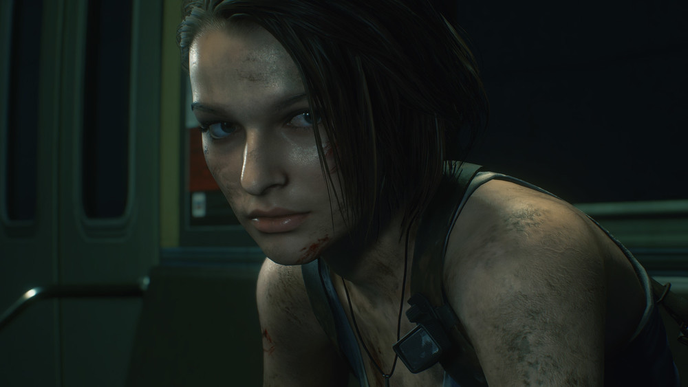 Gros plan de Jill Valentine dans Resident Evil 3, le visage, les bras et les vêtements couverts de saleté et de blessures, dans l’intérieur sombre d’une rame de métro.