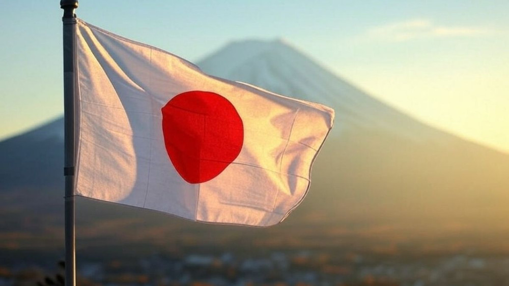 Drapeau du Japon flottant au vent avec le cercle rouge du soleil levant visible sur un fond de montagne, probablement le mont Fuji, éclairée par une lumière de lever ou coucher de soleil.