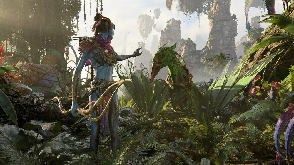 Scène immersive du jeu vidéo Avatar: Frontiers of Pandora, représentant un personnage Na’vi debout dans une jungle luxuriante. Le Na’vi, à la peau bleue, est orné de peintures tribales, de colliers, de bracelets en fibres naturelles et porte un arc fait de bois et de corde. Il tend doucement la main vers une créature ailée verte au bec rouge, semblable à un banshee, symbole emblématique de l’univers d’Avatar. La végétation dense et colorée qui entoure les personnages inclut des fougères géantes, des plantes exotiques aux teintes violettes et des arbres massifs couverts de lianes. En arrière-plan, on distingue les célèbres montagnes flottantes de Pandora, baignées de lumière dorée, renforçant l’ambiance magique et extraterrestre du monde. Une autre monture se devine à gauche, partiellement camouflée par les feuillages.