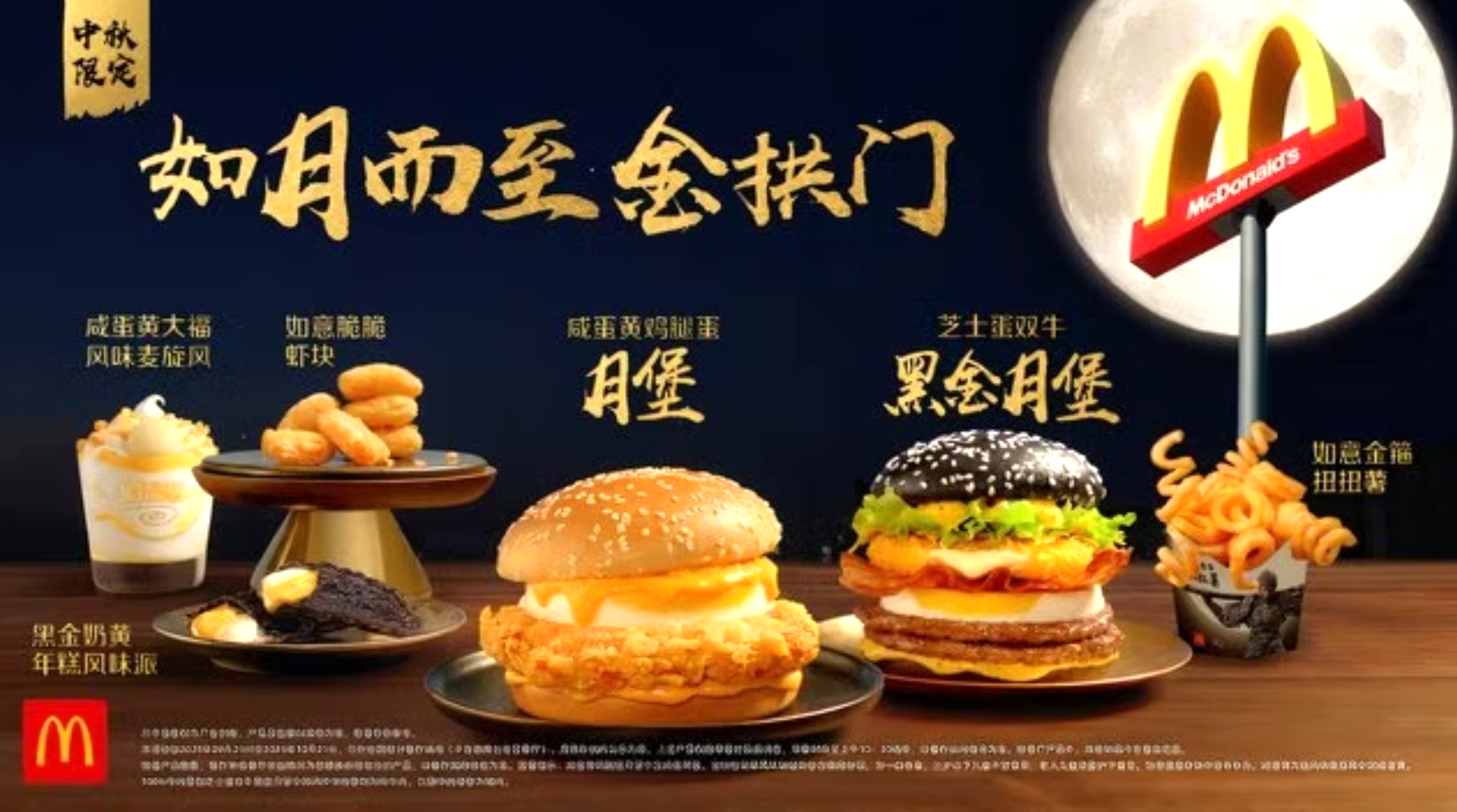 Affiche promotionnelle McDonald’s pour une édition limitée spéciale Fête de la Mi-Automne en Chine, avec un thème visuel centré sur la pleine lune. Sur fond bleu nuit, divers produits sont présentés sur des présentoirs dorés. À gauche, un dessert glacé à la mangue avec chantilly, à côté d’un beignet noir fourré à la crème jaune. À côté, des nuggets de crevette dorés sur un présentoir. Au centre, un burger au poulet frit garni d’un œuf entier et d’une sauce jaune, dans un pain brioché classique. À sa droite, un burger plus élaboré dans un pain noir au sésame, avec deux steaks de bœuf, un œuf, de la laitue, une tranche de fromage et une galette croustillante. À l’extrême droite, un cornet de frites torsadées dans un emballage décoré avec le personnage de Black Myth: Wukong. En arrière-plan, un grand logo McDonald’s est planté devant une pleine lune éclatante. Le texte en chinois doré indique qu’il s’agit d’une offre limitée pour célébrer la saison.