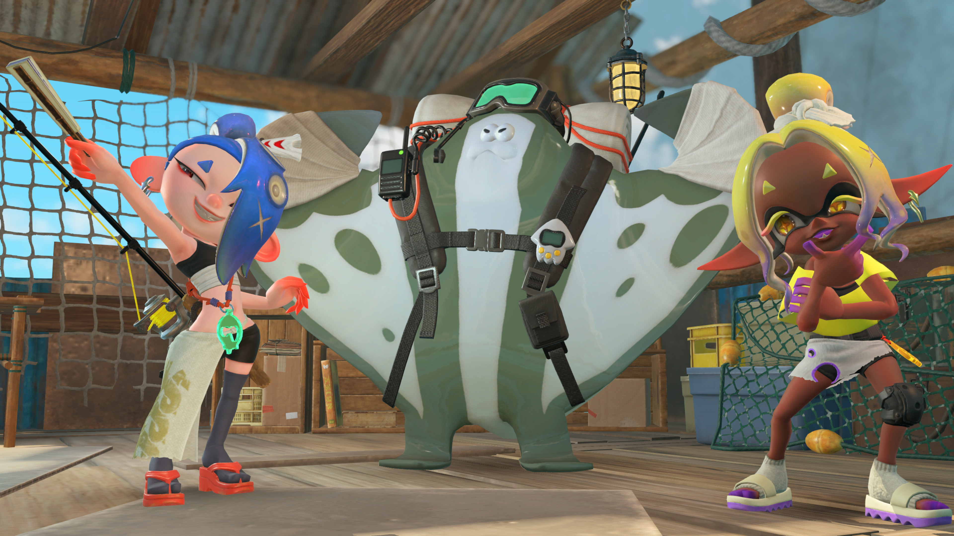 Capture d’écran de Splatoon Raiders montrant deux personnages colorés posant aux côtés d’une grande créature en forme de raie manta équipée de lunettes, d’un harnais et d’accessoires d’exploration. La scène se déroule dans un abri en bois rempli de filets, caisses et matériel de pêche, avec une ambiance légère et tropicale.
