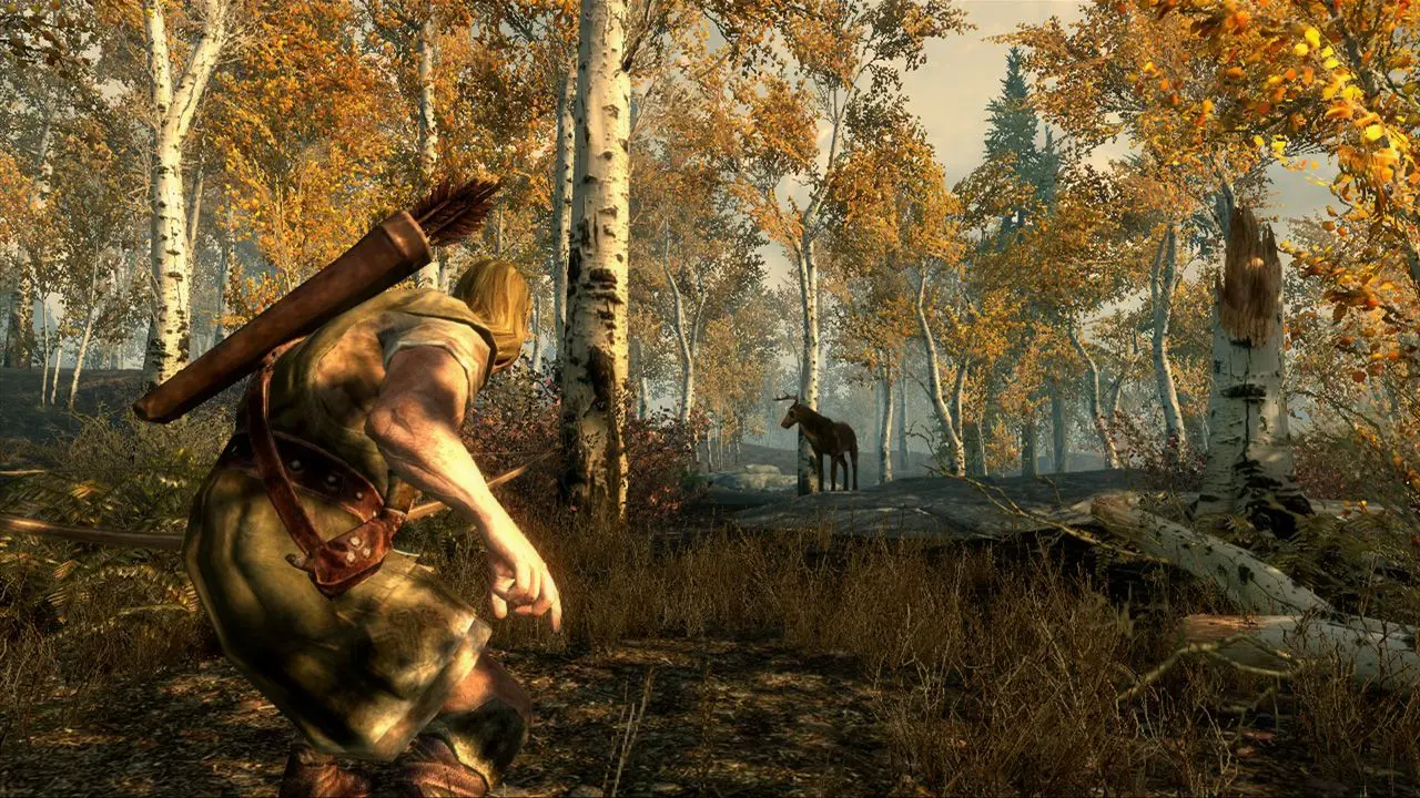 Capture d’écran issue du jeu The Elder Scrolls V: Skyrim, montrant un personnage en pleine traque dans une forêt automnale. À gauche de l’image, un aventurier blond, vu de dos et accroupi, se déplace furtivement à travers les feuillages. Il porte une tunique de cuir, une ceinture utilitaire, et un carquois rempli de flèches sur le dos, suggérant un rôle d’archer ou de rôdeur. L’environnement est riche en détails : une forêt de bouleaux aux feuilles dorées baigne dans une lumière douce et brumeuse. Au centre, à quelques mètres du personnage, un élan se tient immobile sur un rocher, entre les arbres, inconscient du danger imminent. La posture du joueur indique un moment de chasse ou d’approche stratégique, typique du gameplay de Skyrim, qui mêle exploration libre, survie, et immersion dans un monde ouvert médiéval-fantastique. L’image évoque une ambiance paisible mais tendue, où la beauté de la nature contraste avec la possibilité d’une attaque furtive.