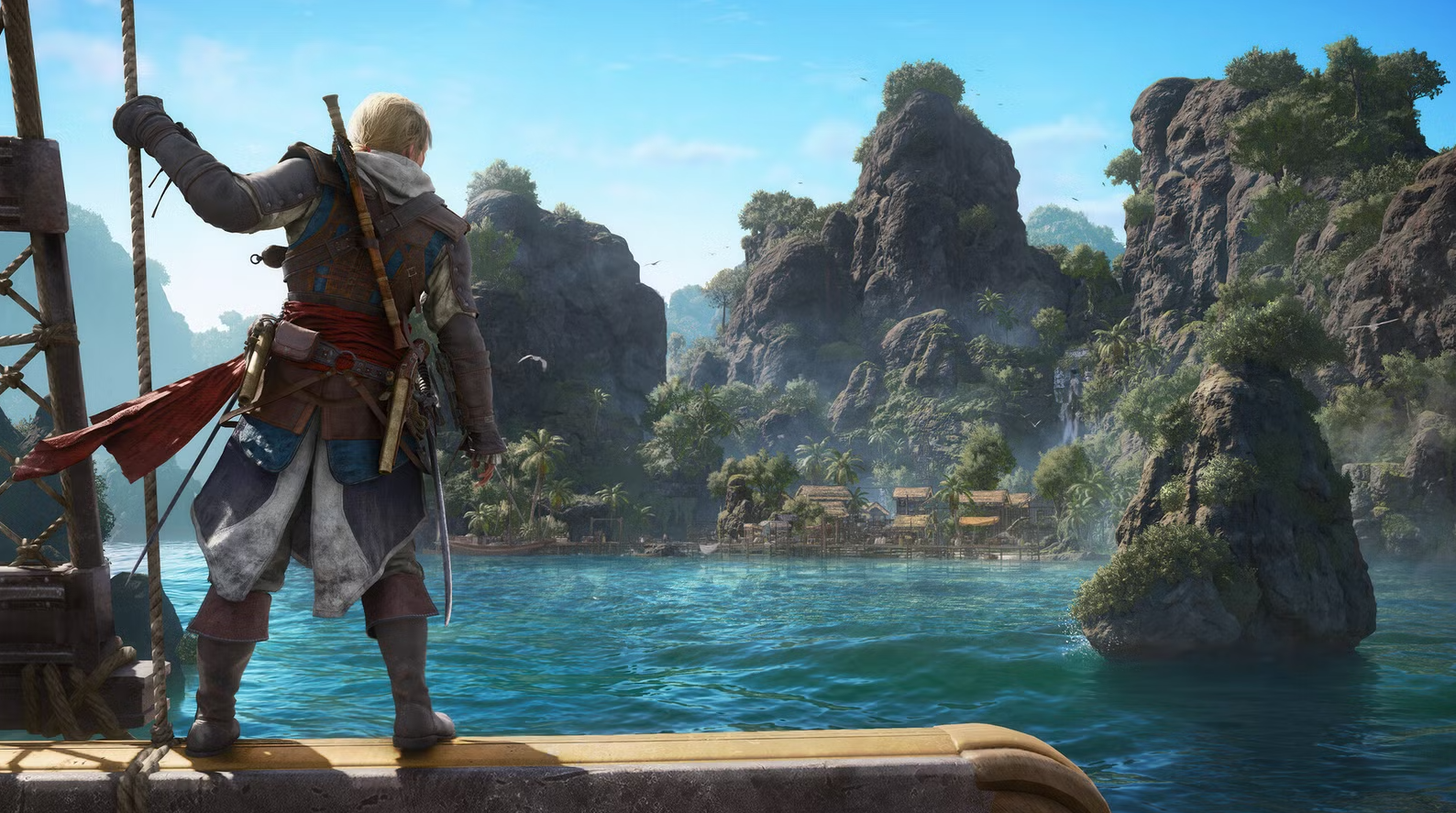 Capture promotionnelle d’Assassin’s Creed IV: Black Flag montrant Edward Kenway de dos sur le pont d’un navire, observant une île tropicale bordée d’une baie, de falaises rocheuses couvertes de végétation et d’un petit village côtier, sous un ciel dégagé évoquant l’exploration et la piraterie dans les Caraïbes.